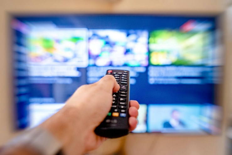 Uomo cambia canale con il telecomando
